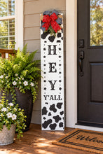 Load image into Gallery viewer, Black-and-white cow print “Hey Y’All” wooden porch leaner with red bandana bows and greenery.