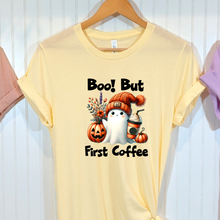 Load image into Gallery viewer, French Vanilla Bella Canvas t shirt with an image of a ghost holding coffee and pumpkins near with the words "Boo! But First Coffee" in black.